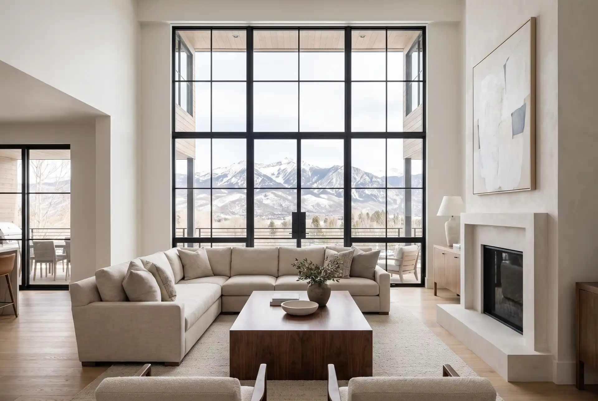 A double-height living room with black steel windows looking out to snow-capped mountains